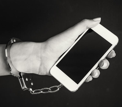 image of hand handcuffed to smart phone to symbolize technology addiction