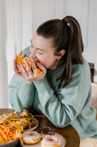 image of woman eating junk food to illustrate the idea of Big Food