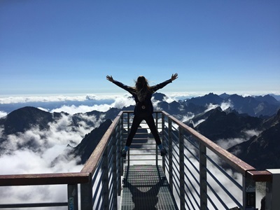 image of a woman at the peak of a hike to conceptualize what's a good life